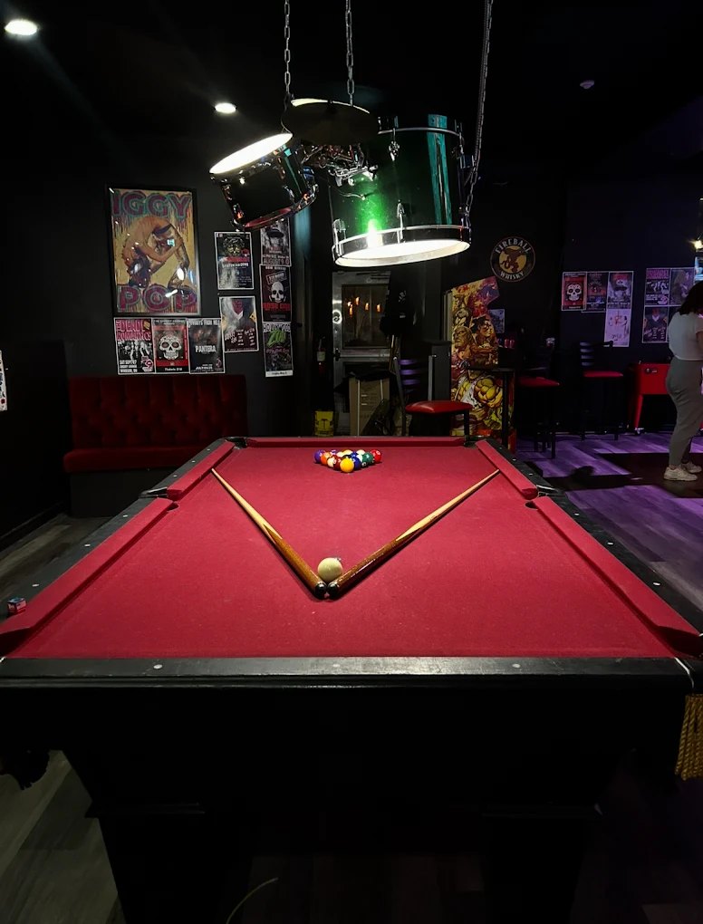 The red pool table under green lamps